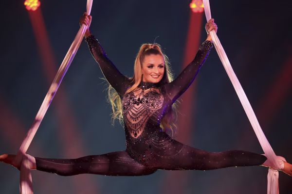 An aerialist performing on suspended aerial silks