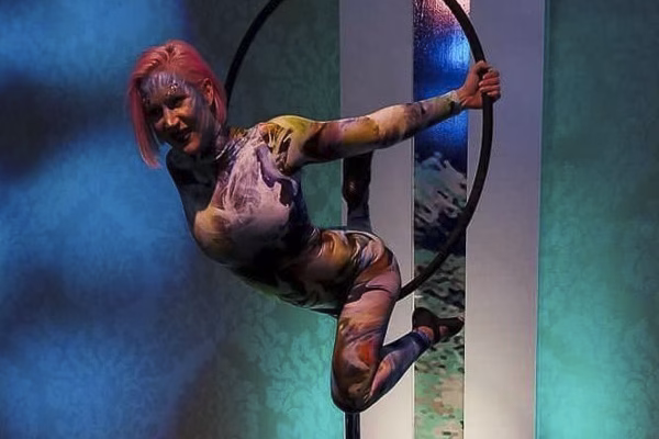Graceful aerialist performing on a lollipop lyra, suspended elegantly in the air with a vibrant, colorful design.